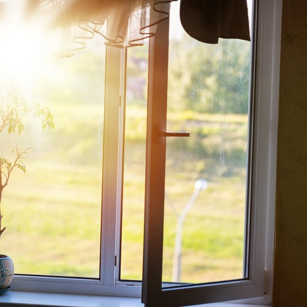 Geöffnetes Fenster mit einfallender Sonne und Blick ins Grüne