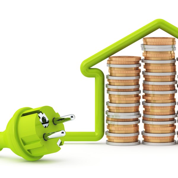Grüner Stromstecker vor Münzstapeln in Hausform als Energiespar-Symbol